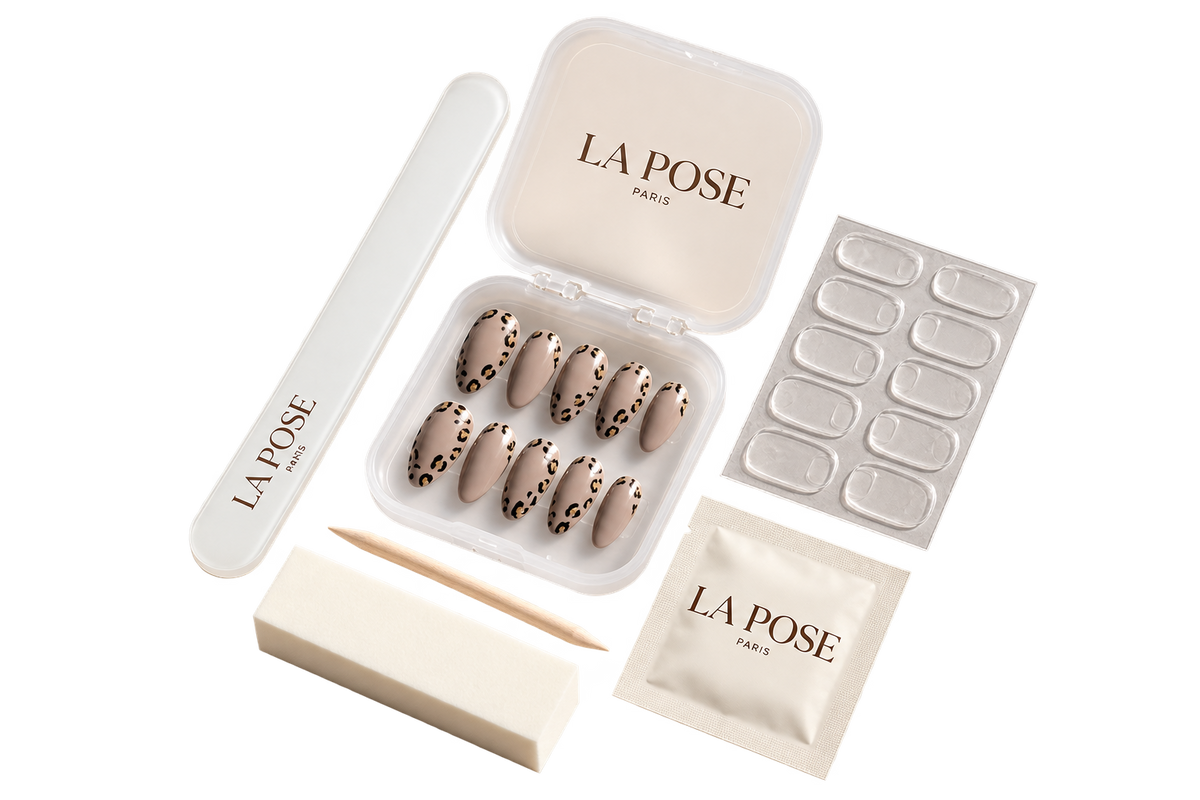 Le coffret press-on La Pose et son contenu : boîtier d’ongles nude à motif léopard, lime en verre, polissoir, bâtonnet de buis, planche de pastilles adhésives et lingette de préparation
