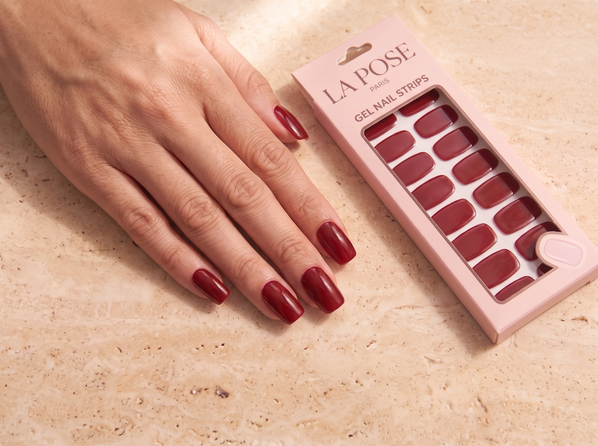 Manucure rouge La Pose et son étui rose fermé sur une pierre claire.